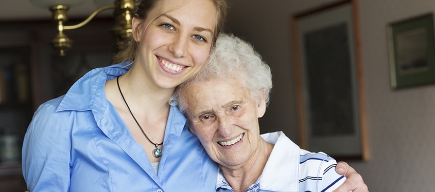 A younger woman hugging an older woman in a senior living community