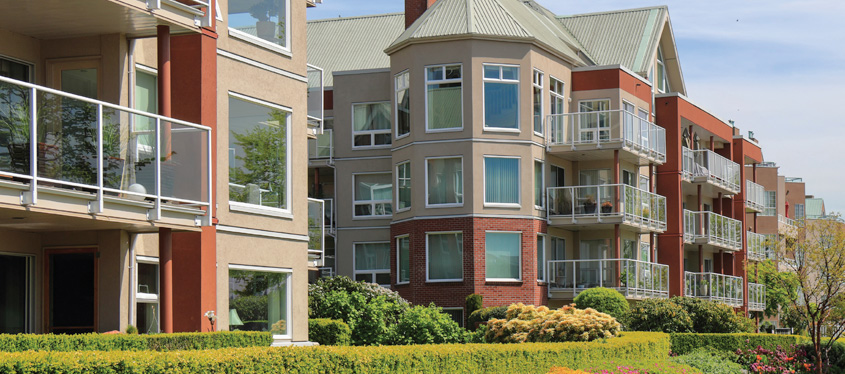 A multifamily community comprised of several modern brick buildings in a row on the same street.